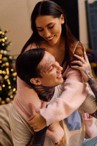 A loving couple enjoys a tender embrace filled with laughter and warmth indoors during winter.
