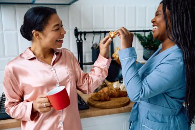 Women enjoy breakfast together, sharing smiles and laughter in a cozy kitchen atmosphere. clipart