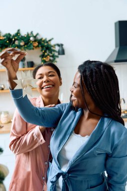 İki kadın sevinçle evlerini dekore ederek sıcak bir ortam yaratıyor..