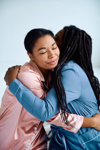 Two women share a warm embrace, expressing their love and happiness in a serene space.