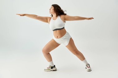 Kendine güveni tam genç bir kadın, güzel beyaz iç çamaşırlarıyla basit bir arkaplanda güzelliğini sergiliyor..