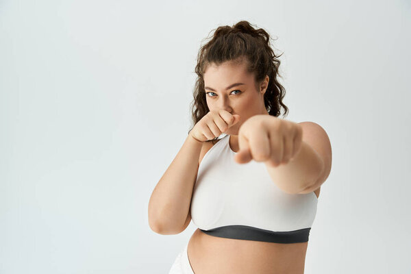 Confident plus size woman models chic underwear, radiating beauty and style in bright light.