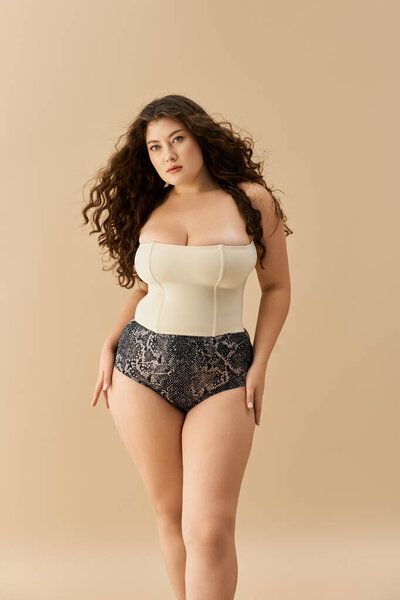 Stylish plus size woman poses confidently in fashionable underwear against a soft backdrop
