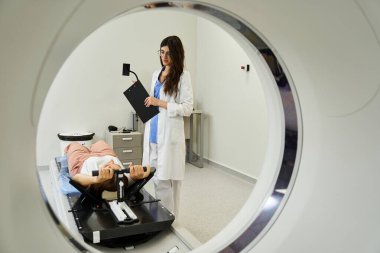 Laboratuvar önlüklü bir doktor bir hastayı hastane odasında MRI taramasına hazırlar..