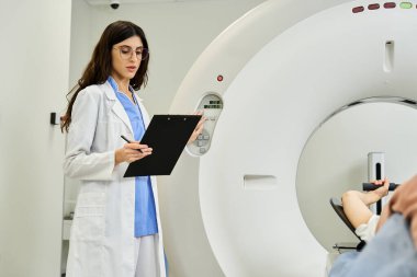 Laboratuvar önlüklü bir kadın doktor MRI makinesinin yanında duruyor ve hasta teşhisine hazırlanıyor..