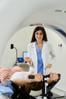 Laboratuvar önlüklü bir doktor, bir sağlık merkezinde MRI taramasına hazırlanan bir hastaya destek olur..