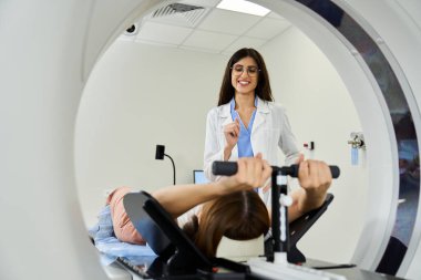 Kadın doktor, hastaya MR çekilirken yardımcı oluyor..