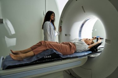 Şefkatli bir kadın doktor, hastanede MRI taraması yapılan bir hastaya destek olur..