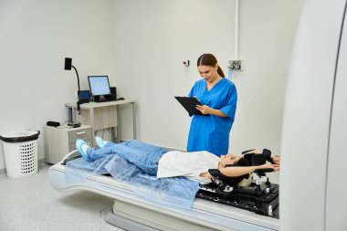 Laboratuvar önlüklü bir doktor hastanede MR çektiren bir hastayı denetliyor..