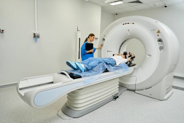Kadın doktor, hastayı MRI makinesine sokup bir hastanede sağlık muayenesi yaptırıyor..