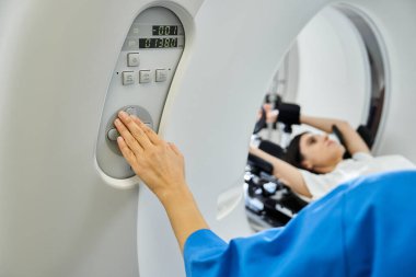 Laboratuvar önlüklü bir doktor, hasta taranırken MRI makinesini çalıştırıyor..