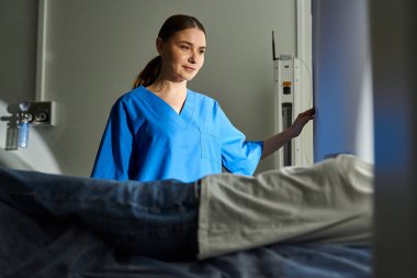 Laboratuvar önlüklü bir doktor, hastanın MR çekmesine yardım eder..