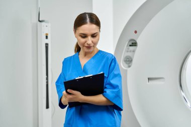 Önlüklü çekici kadın doktor, radyoloji alanındaki hasta teşhislerini titizlikle gözden geçiriyor..