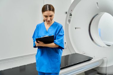 Laboratuvar önlüklü bir kadın doktor MRI makinesinde hasta bilgilerini inceliyor..
