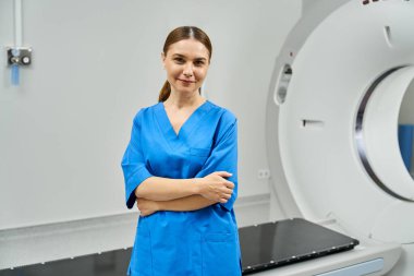 Kadın doktor, bir hastanede MRI makinesinin yanında güvenle duruyor ve uzmanlığını gösteriyor..