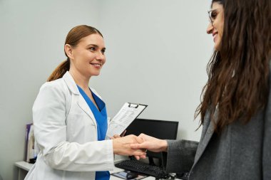 Laboratuvar önlüklü bir jinekolog klinikte kadın bir hastayla sağlık sorunlarını tartışıyor..