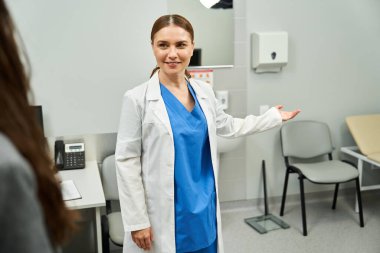 Laboratuvar önlüklü bir jinekolog modern bir klinikte kadın bir hastayla meşgul oluyor..
