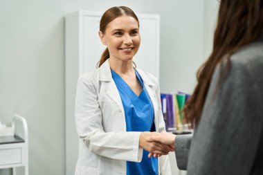 Bir jinekolog modern bir klinikte rutin bir kontrol sırasında kadın bir hastayı sıcak bir şekilde karşılar..