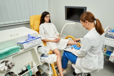 Bir jinekolog klinikte kadın bir hastayı muayene ediyor..