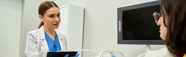 Laboratuvar önlüklü bir jinekolog klinikte bir kadın hastayla sağlık sorunlarını tartışıyor..