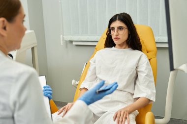 Çağdaş bir klinikte, jinekolog bir hastayla teşhis seçeneklerini tartışır..