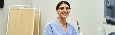 Mavi önlüklü yetenekli bir jinekolog çağdaş bir klinikte sıcak bir gülümseme sergiliyor..