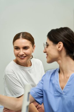 Bir sağlık uzmanı, sıcacık bir klinikte kadın bir hastayla sağlık sorunlarını tartışır..