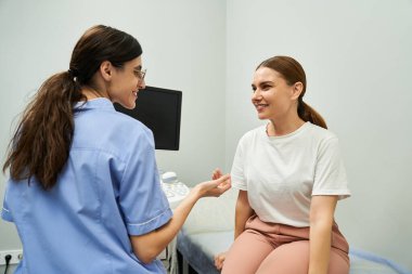 Bir jinekolog, çağdaş bir klinikte bir hastayla sağlık sorunlarını tartışıyor..