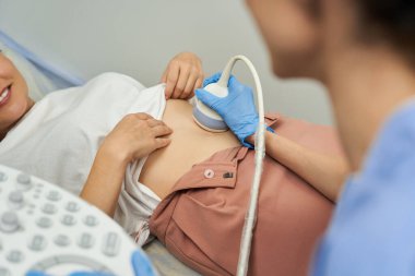 Bir jinekolog, parlak bir klinikte kadın bir hastayla ultrason muayenesi yapıyor..