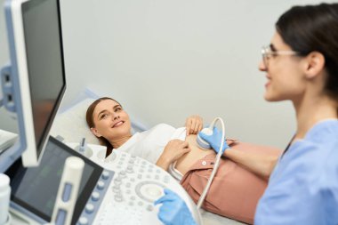 Bir jinekolog modern bir klinikte kadın bir hastaya ultrason uygular..