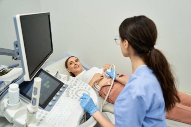 Bir jinekolog, klinikte çok önemli bir sağlık muayenesi sırasında kadın bir hastaya yardım eder..