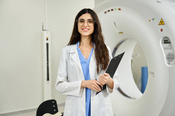 Attractive doctor with clipboard stands confidently beside MRI equipment in hospital.