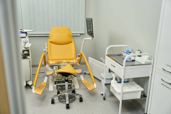 A gynecologist office with a yellow chair and medical tools for female health.