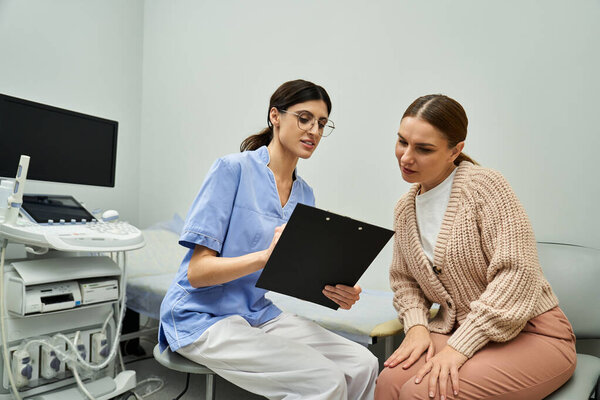 A gynecologist discusses important health details with a female patient in a contemporary clinic.