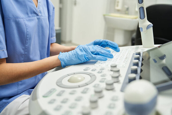 A gynecologist in a lab coat uses ultrasound equipment to assess female health in a clinic.