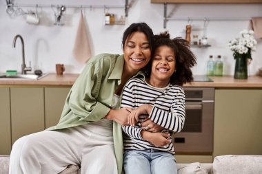 A mother and her daughter embrace with warm smiles, enjoying a playful moment together. clipart