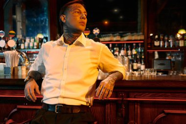 Dövmeli genç bir adam barda rahatlar, gece boyunca kendine güveni tamdır..