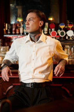 Yakışıklı genç yetişkin barda rahatlıyor, gece hayatının tadını çıkarırken dövmelerini sergiliyor..