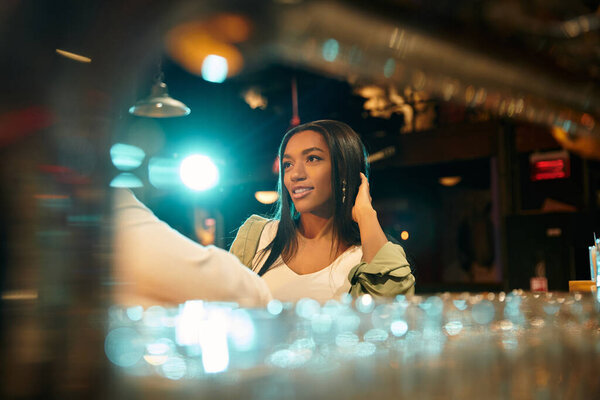 A young multicultural couple shares a joyful moment during their date at the bar.