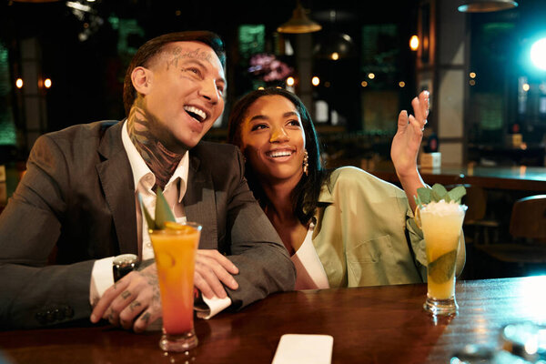 A young couple shares laughter and drinks during their night out at a lively bar.