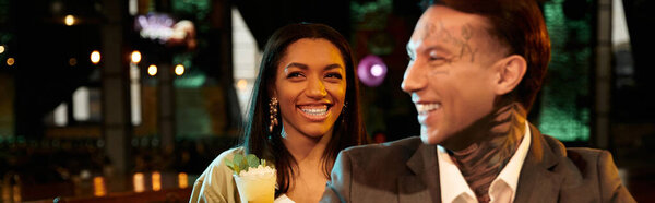 Живая мультикультурная пара делится радостными моментами ночи в оживленном баре.