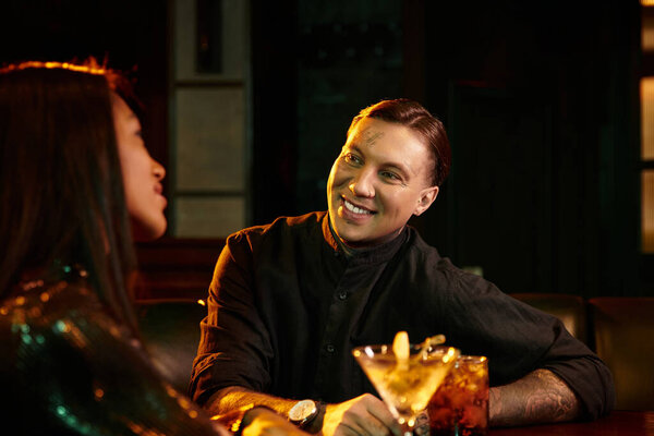 A young couple shares laughter and drinks during a cozy night out at the bar.