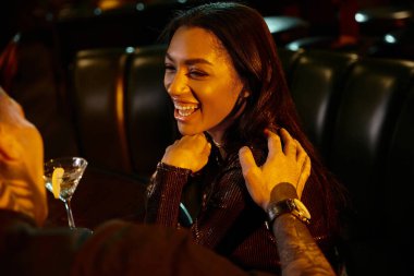 A young couple shares laughter and connection over drinks in a vibrant bar atmosphere. clipart