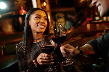 A young couple shares a joyful moment while clinking their wine glasses during a date. clipart