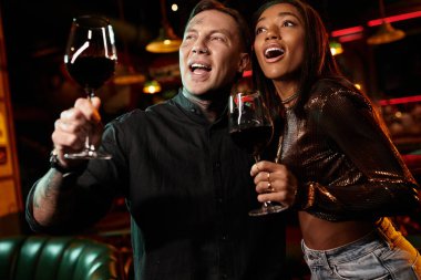 Genç bir çift, canlı bir bar atmosferinde buluşmalarını kutlarken neşe saçıyor..