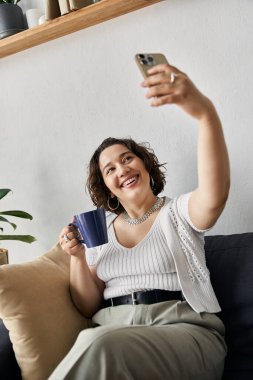 Güzel genç bir kadın şık dairesinde selfie çekerken kahvesinin tadını çıkarıyor..