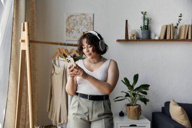 Kıvırcık saçlı genç bir kadın modern ortamında müzik dinlerken rahatlıyor..