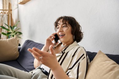 Kıvırcık saçlı kadın evde canlı bir telefon görüşmesi yapıyor, pozitif enerji yayıyor..