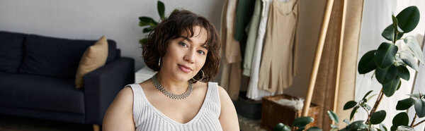 Молодая женщина с вьющимися волосами расслабляется в своей современной квартире, обнимая модную атмосферу, баннер