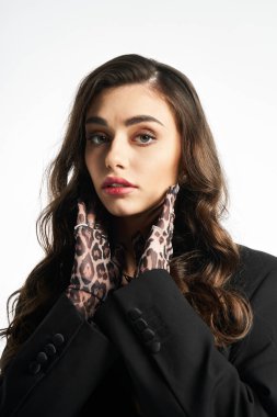 Güzel bir kadın, leopar desenli eldivenlerle, kendine güvenerek poz veriyor. Stil ve zarafet yayıyor..